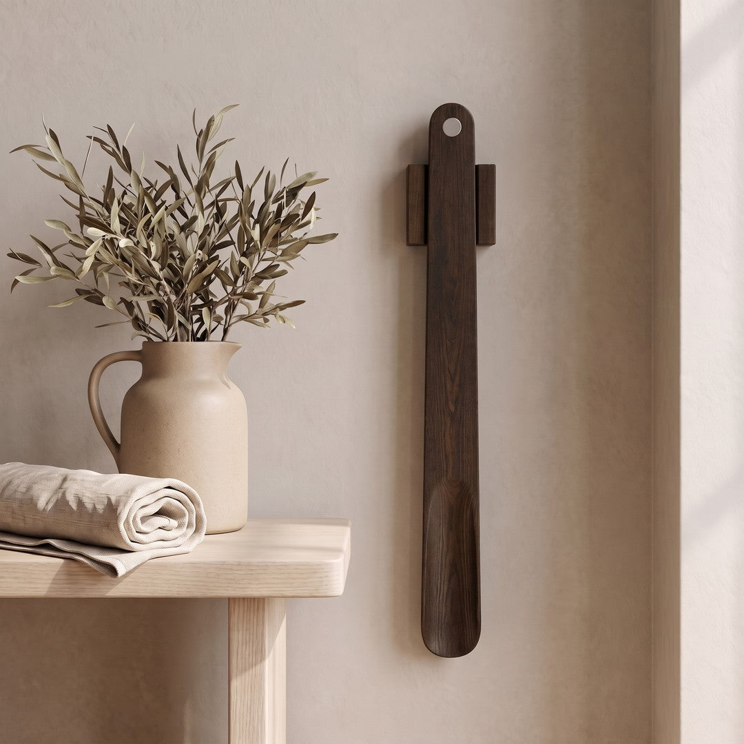 KLIVA magnetic shoehorn hanging on a plaster wall beside a small side table