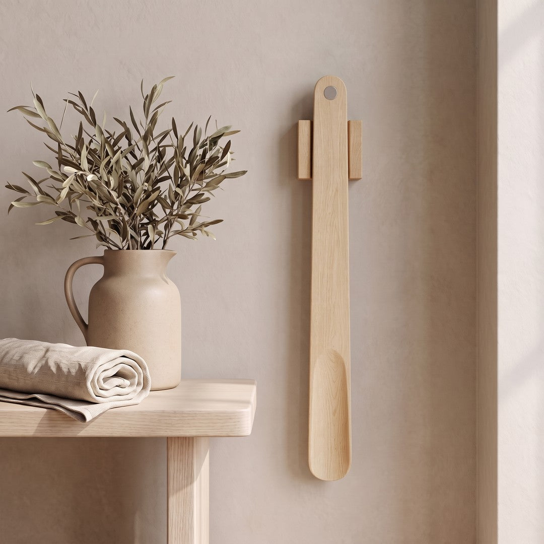 KLIVA magnetic shoehorn hanging on a plaster wall beside a small side table