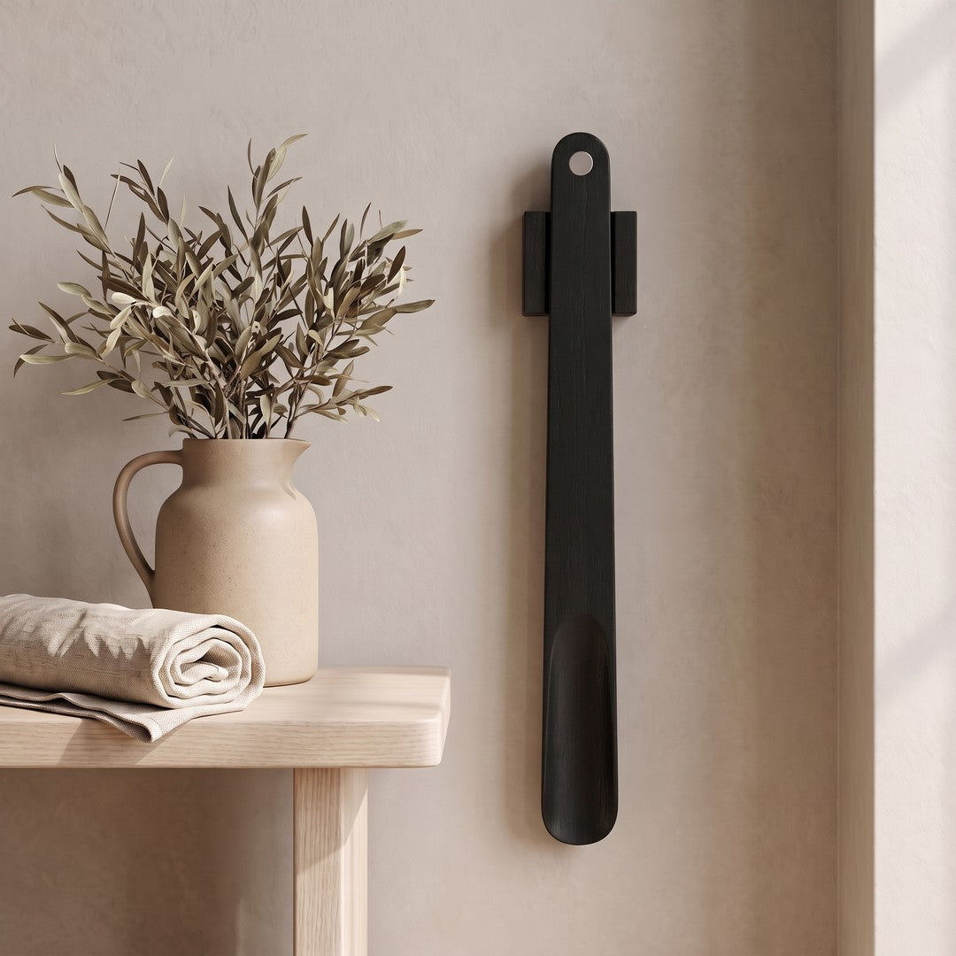 KLIVA magnetic shoehorn hanging on a plaster wall beside a small side table
