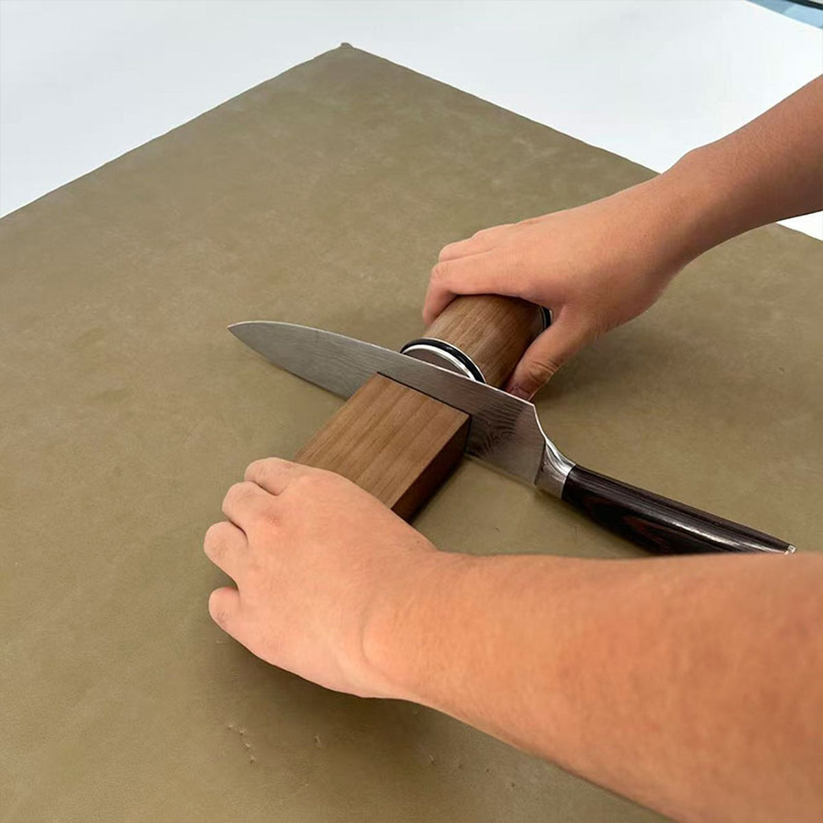 Rolling the SLIPA sharpener along a chef's knife held on the magnetic block
