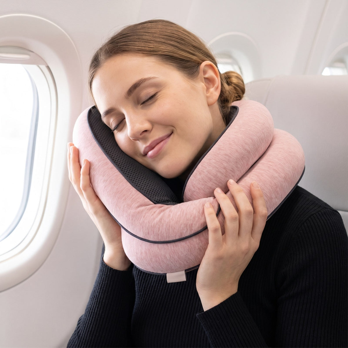 Woman resting on the blush SLUMRA pillow at a plane window