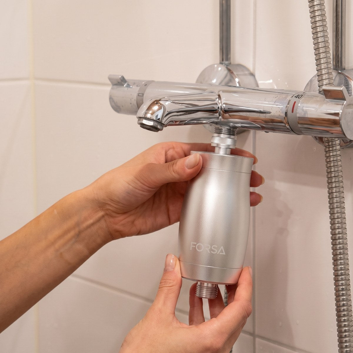 Hands screwing the FORSA filter between the shower tap and the hose