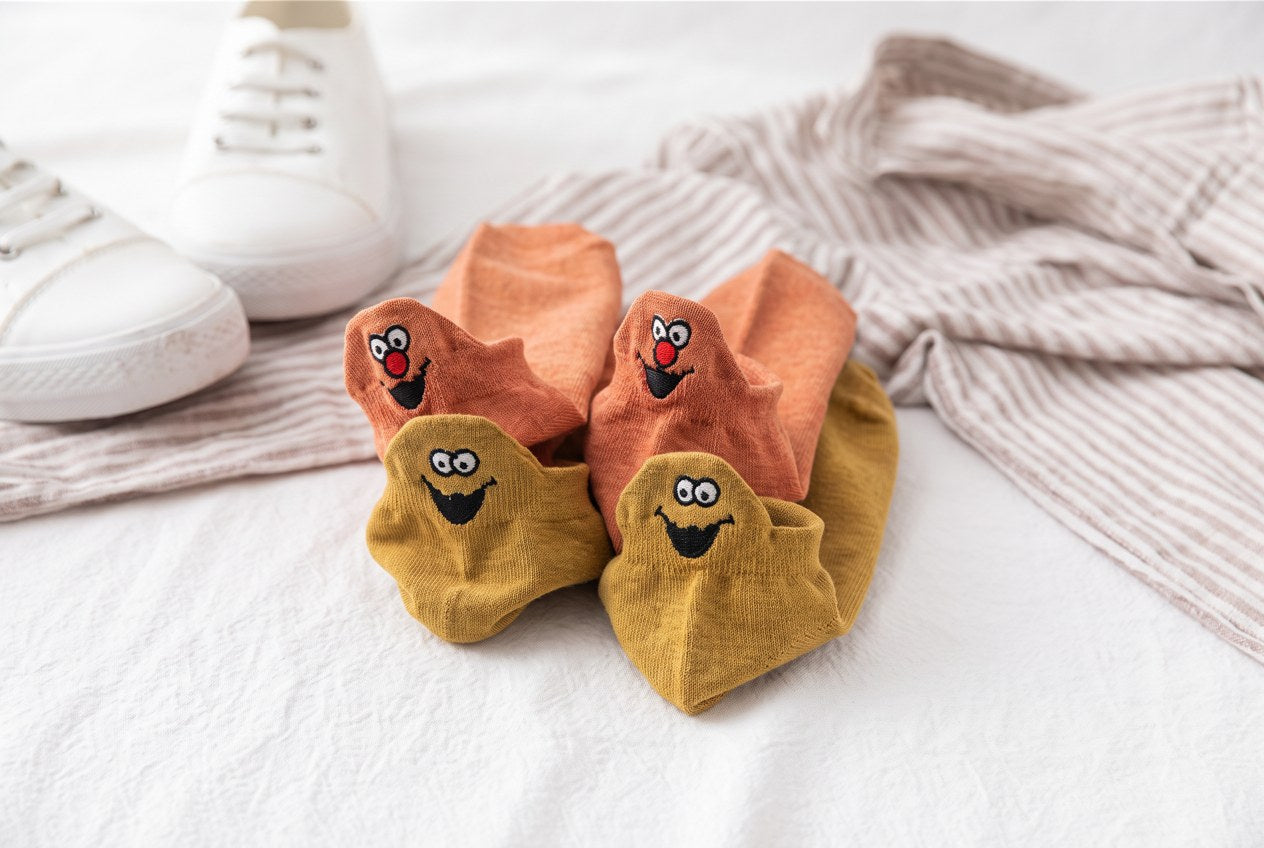 Orange and mustard TASSA socks with smiling faces on the heel tabs