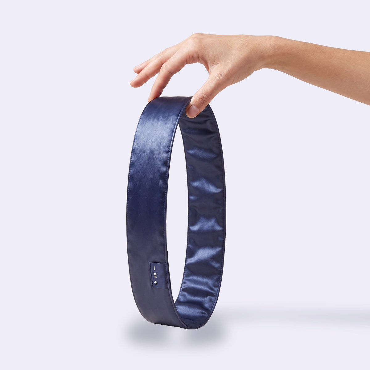 The navy satin Hushband headband held in a hand