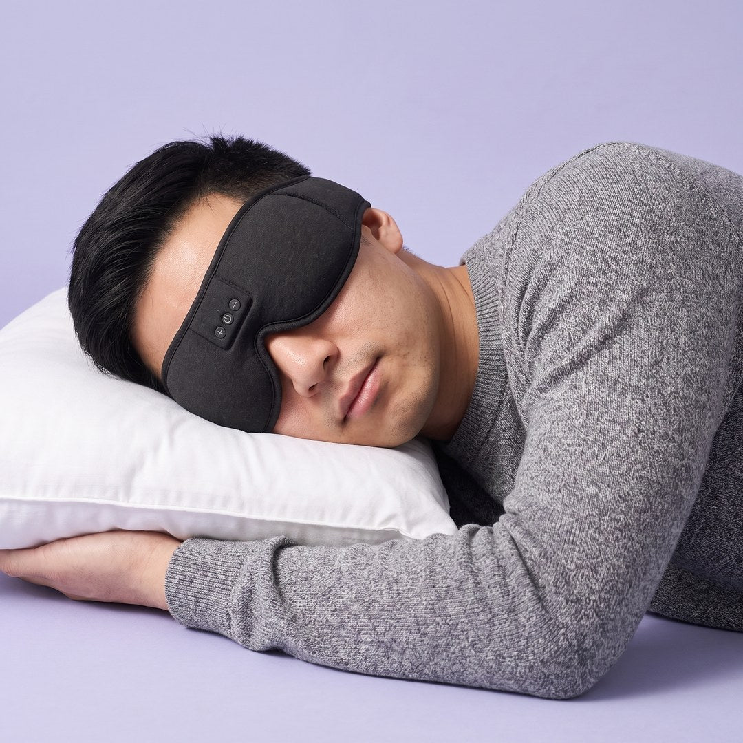 A man sleeping on his side in a black Hushband sleep mask