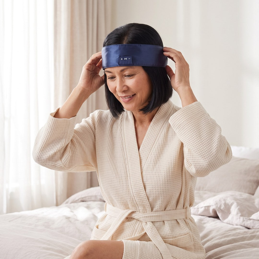 A woman sliding the navy satin Hushband onto her forehead