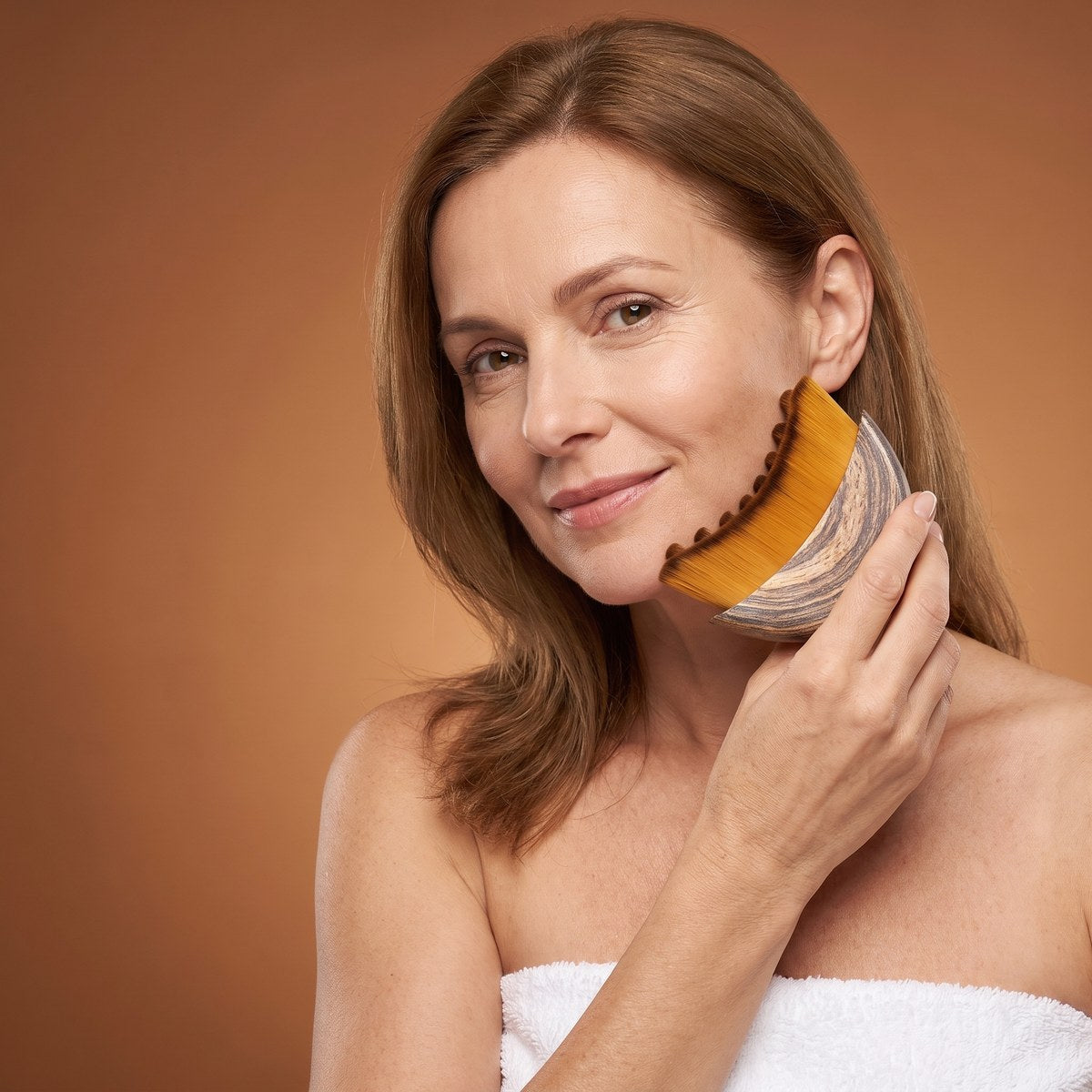 A woman sweeping the brush up along her jawline