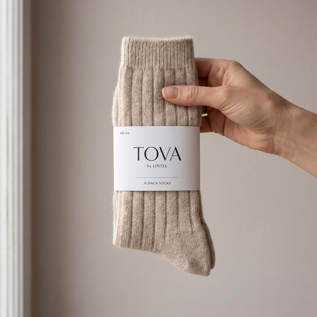 Beige — a pair of TOVA by LINTEL alpaca socks in hand