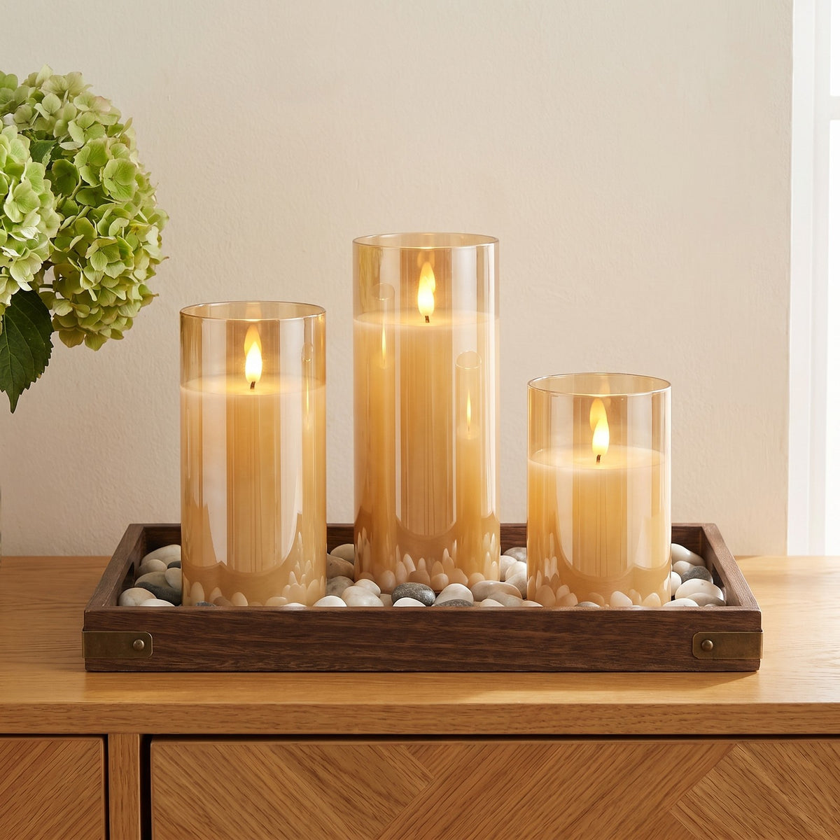 Amber VEKE candles in a wooden pebble tray on an oak sideboard
